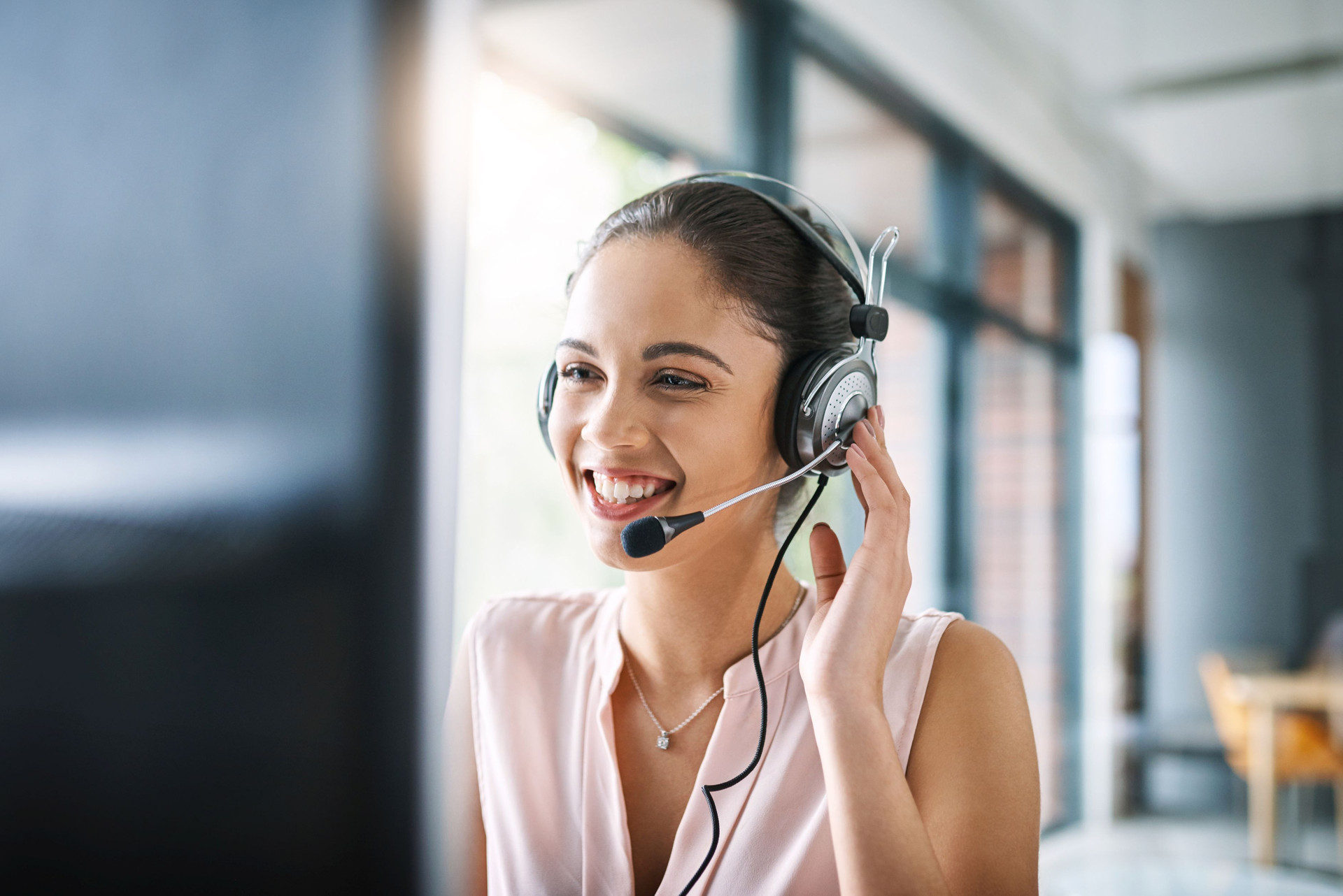 Ansprechpartnerin mit Headset vor einem PC