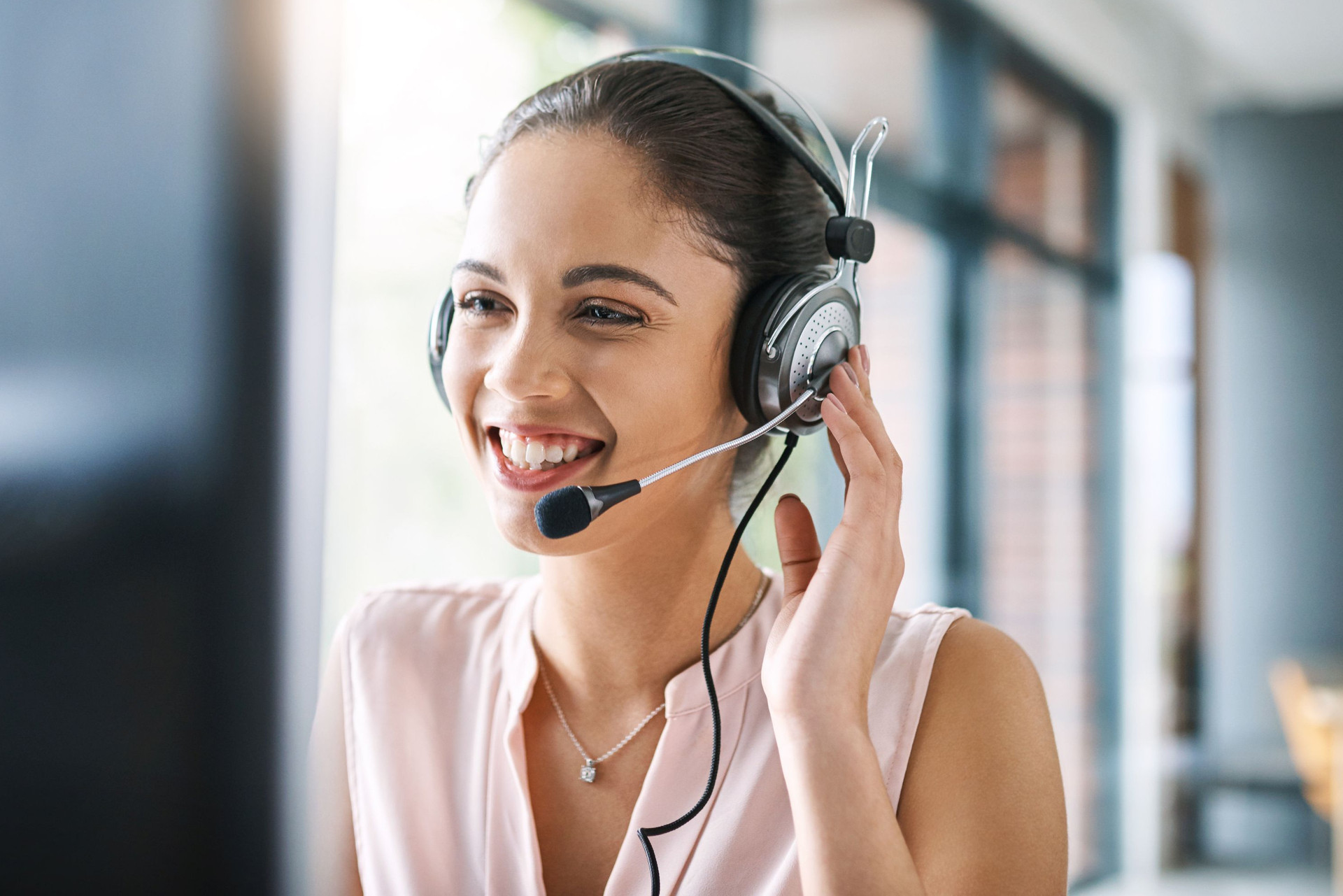 Ansprechpartnerin mit Headset vor einem PC